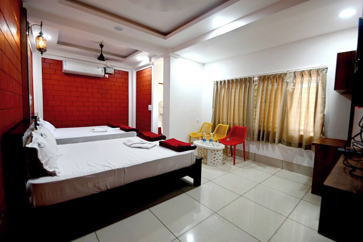 A hotel room with a large bed, a small round table, a TV, and a window with curtains.
