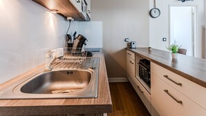 A modern kitchen with a stainless steel sink, wooden countertop, and a built-in oven. - Arcachon Aiguillon: 2-Bedroom with Balconies and Parking (Arcachon)