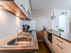 Eine moderne Küche mit Spüle aus Edelstahl, einer Holzarbeitsplatte und einem eingebauten Backofen.