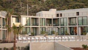 A modern hotel with a pool area, multiple balconies, and a view of a hilly landscape. - Inanna Resort  (Batroun)