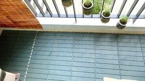 A balcony with a metal railing, potted plants, and a view of a green landscape. - Spacious Luxury City View with Pool - Korean Town, closed by City center & SECC (Thành phố Hồ Chí Minh)