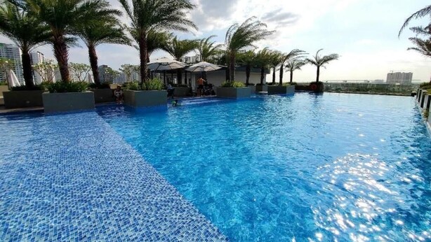 A swimming pool with clear blue water, surrounded by palm trees and lounge chairs. - Spacious Luxury City View with Pool - Korean Town, closed by City center & SECC (Thành phố Hồ Chí Minh)