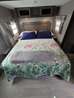 Ein Bett mit floralem Bettbezug, zwei Kissen und einer Decke.