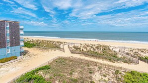 Ein Strandhotel mit Sandstrand, Holzzaun und blauem Himmel.