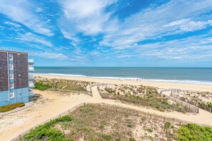 A beachfront hotel with a sandy beach, a wooden fence, and a clear blue sky. - Beautiful remodel one Bedroom Ocean Front with outdoor pool (Ocean City)