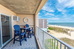 A balcony with a view of the beach, a table with chairs, and a life ring on the wall. - Beautiful remodel one Bedroom Ocean Front with outdoor pool (Ocean City)