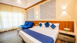 Une chambre d’hôtel avec un grand lit, un canapé bleu, une petite table et une table de chevet avec une lampe.