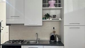 A modern kitchen with white cabinets, a black stove, and a sink. - New Florence Smart Flat - Parking & Tram Stop (Firenze)