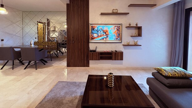 A modern living room with a large flat-screen TV, a wooden coffee table, and a sofa. - Luxury studio with swimming pool opposite the station (Marrakech)