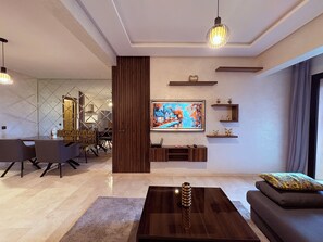 Un salon moderne avec un grand téléviseur à écran plat, une table basse en bois et un canapé.