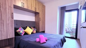 A modern bedroom with a large bed, wooden wardrobe, and a balcony view. - Luxury studio with swimming pool opposite the station (Marrakech)