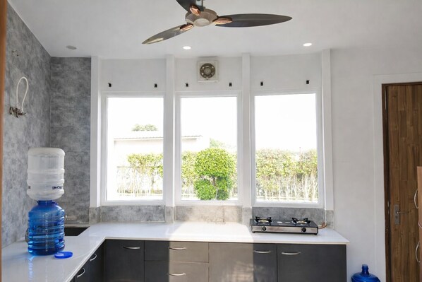A kitchen with a water dispenser, a stove, and large windows. - Wise One Choice (Noida)