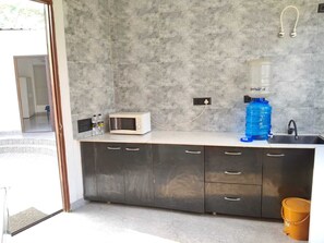 A modern kitchen with a microwave, water dispenser, and sink. - Wise One Choice (Noida)