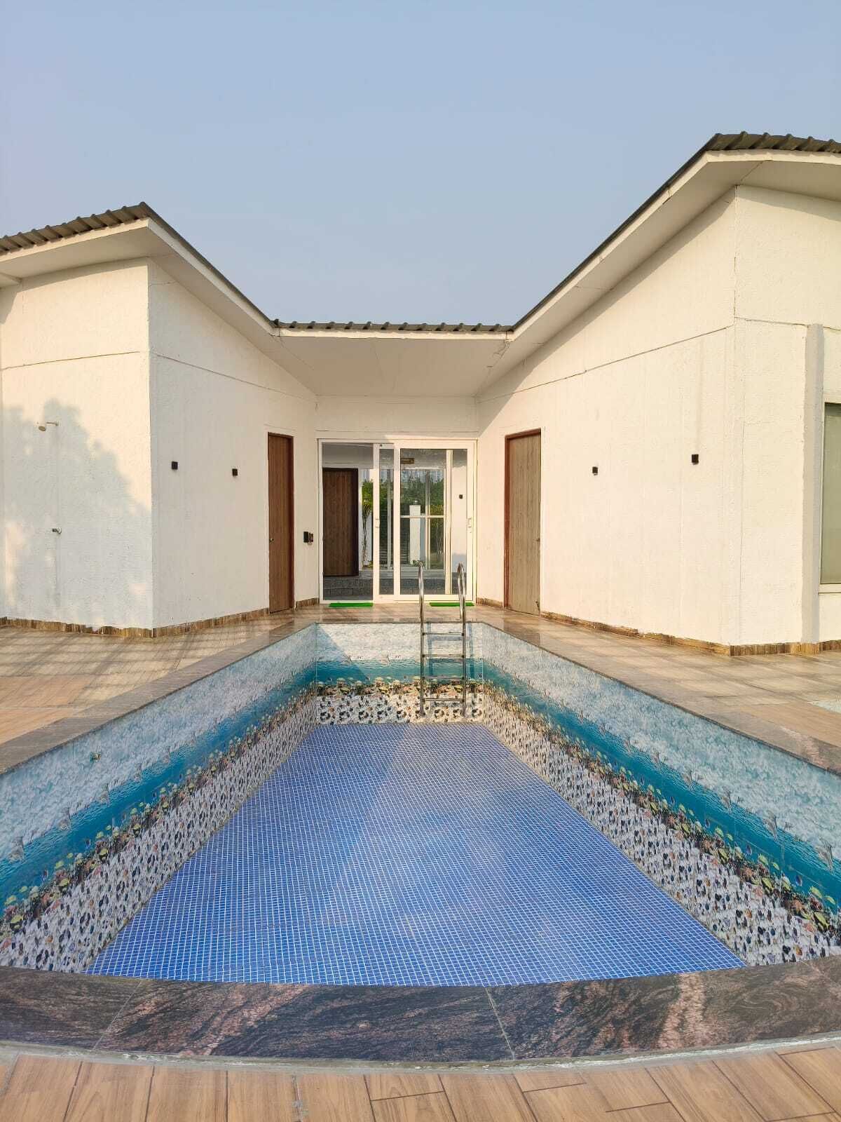 A swimming pool with a tiled deck, surrounded by a building with a tiled roof and white walls.
