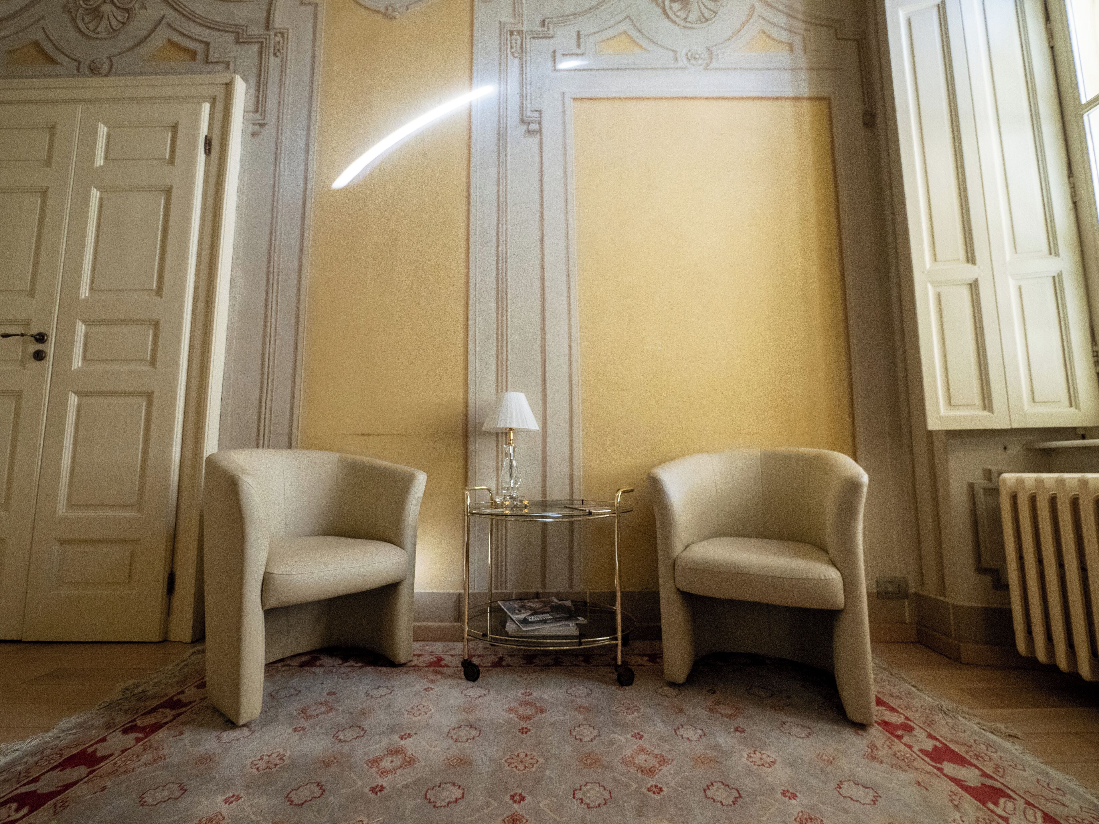 A room with two armchairs, a small side table with a lamp, and a patterned carpet.