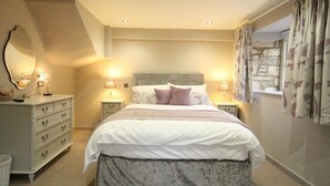 A bedroom with a bed, nightstands, a dresser, and a mirror. - The Coach House (Burford)