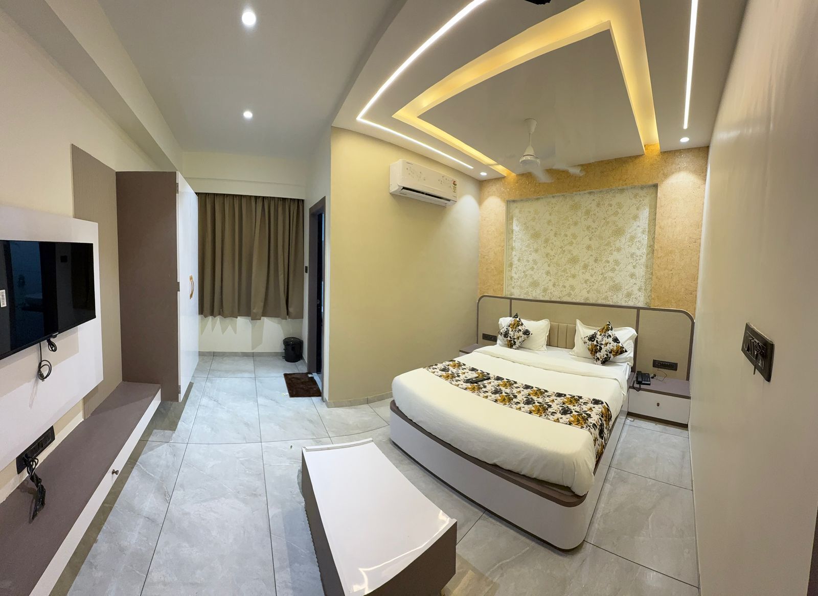 Habitación de hotel moderna con una cama grande, televisión de pantalla plana y ventilador de techo.