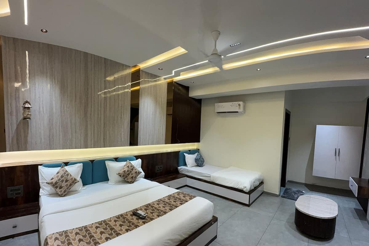 A modern hotel room with a large bed, a sofa bed, a small round table, and a wardrobe.