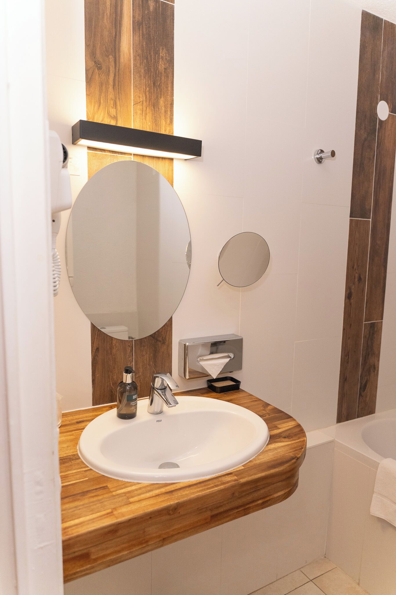 Un baño con tocador de madera, un espejo grande, un lavamanos y una zona de ducha.
