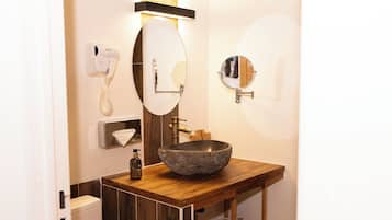 Un baño con tocador de madera, un espejo grande, un inodoro y un dispensador de toallas.