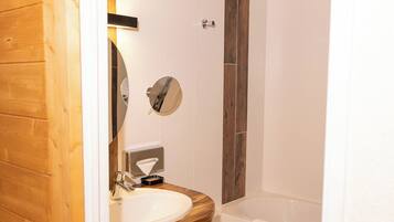 Une salle de bain avec une porte en bois, un lavabo, un miroir, une serviette et une baignoire.