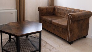 Un salon avec un canapé en cuir marron, une table basse en bois et un tapis beige.