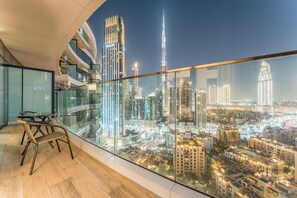 Een modern interieur met een glazen balkon met uitzicht op een stadsgezicht 's nachts, met verlichte wolkenkrabbers en een zicht op het stedelijk gebied.