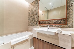Une salle de bain moderne avec une baignoire, un grand miroir et un meuble-lavabo.