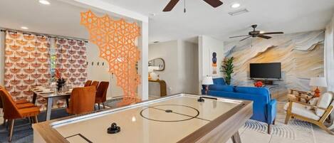 A living room with a pool table, blue sofa, and a TV.