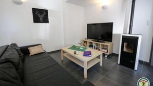 Een moderne woonkamer met een bank, een salontafel, een flatscreen televisie en een open haard.