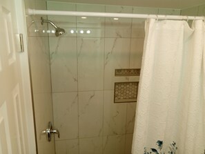 A bathroom with a shower, a door, and a curtain. - Unit 101 - Vinny's Place (Ground Floor/1 bedroom) (Treasure Island)