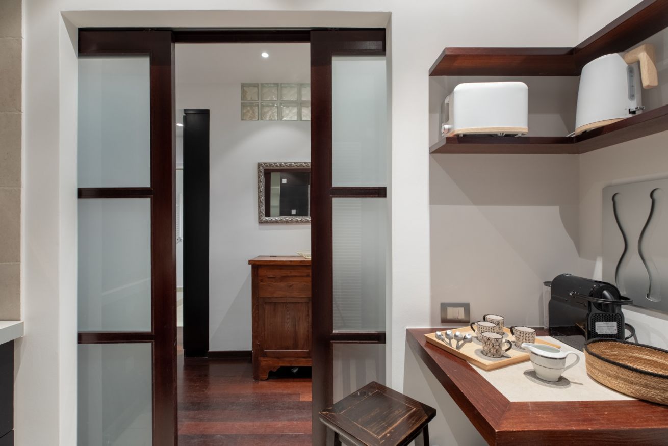 A modern kitchen with a wooden countertop, a coffee machine, and a small cabinet.