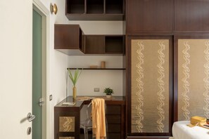 A room with a desk, chair, and a bed. There is a door on the left, a shelf above the desk, and a decorative panel on the right. - iFlat | Elegant Roman Retreat by the Vatican (Roma)