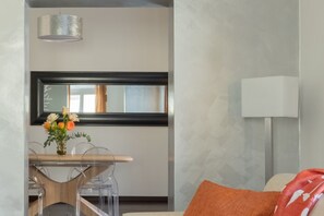A modern room with a dining table, chairs, a vase with flowers, a hanging light fixture, and a white lamp. - iFlat | Elegant Roman Retreat by the Vatican (Roma)