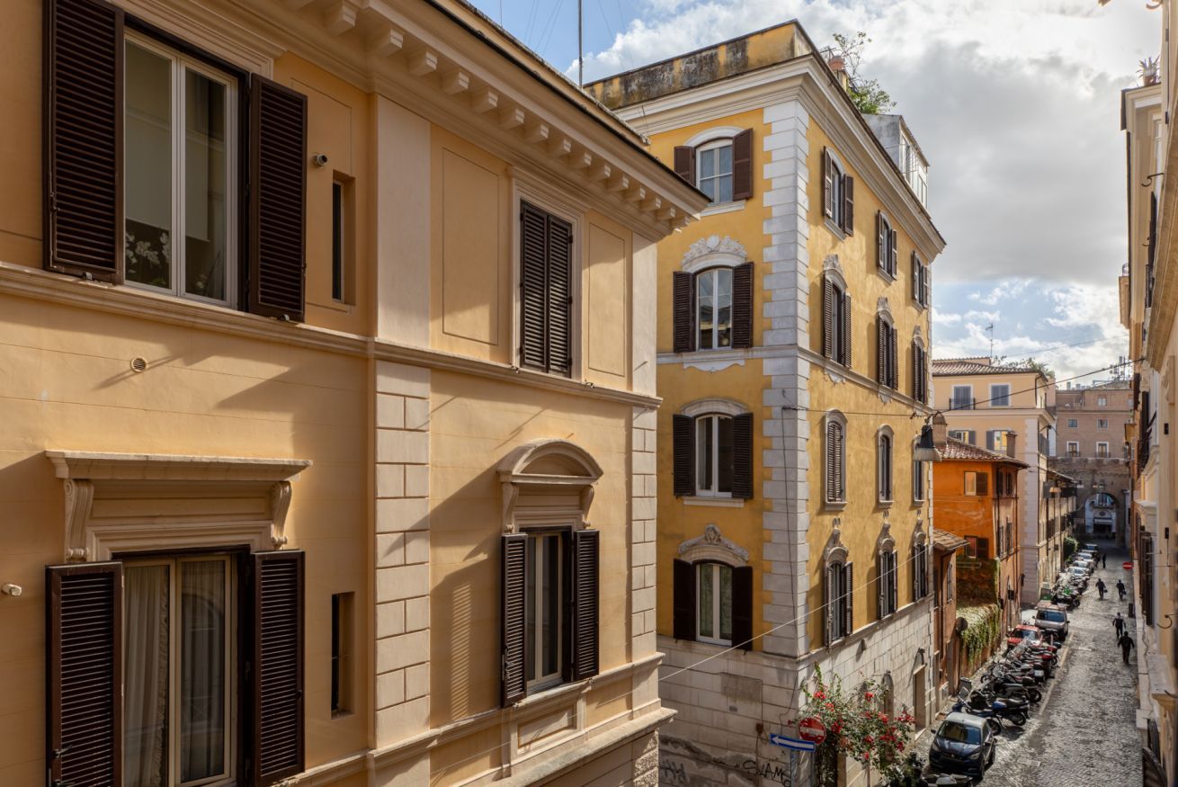 A narrow street lined with historic buildings featuring traditional architecture, shutters, and a cobblestone road.