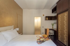Ein Hotelzimmer mit Bett, Nachttisch, Schreibtisch und Kleiderschrank.