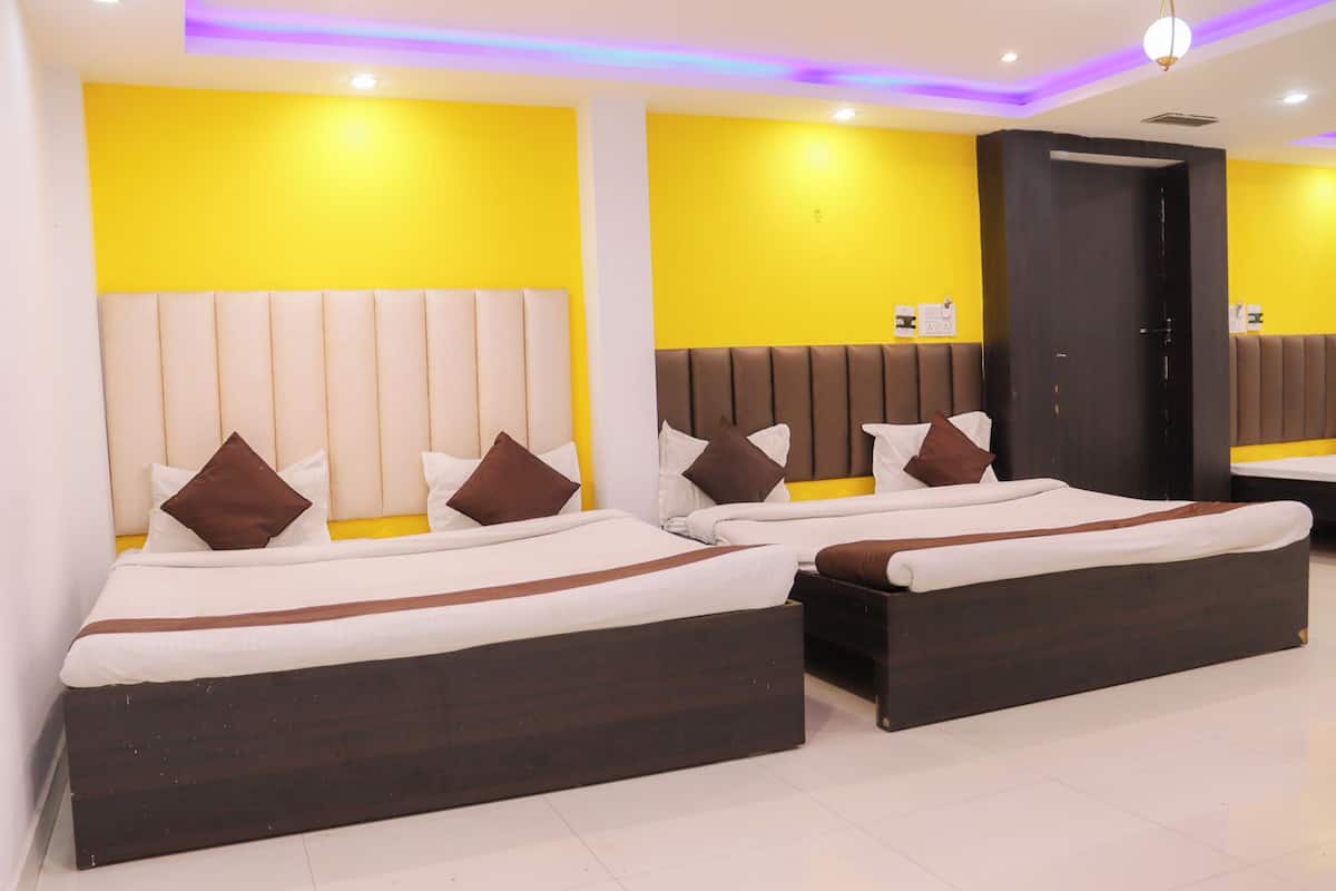 A hotel room with two beds, a dark wooden headboard, and a yellow accent wall.