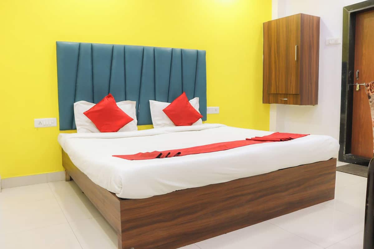 A bed with a wooden frame, a teal upholstered headboard, and red and white pillows.