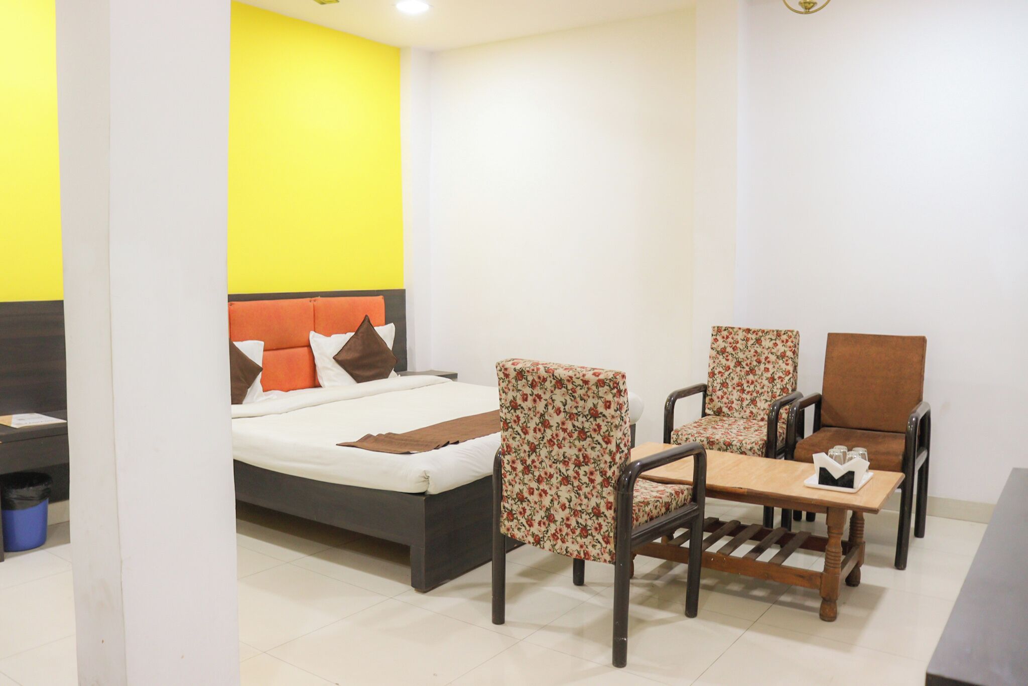 A room with a bed, two chairs, a small table, and a nightstand.