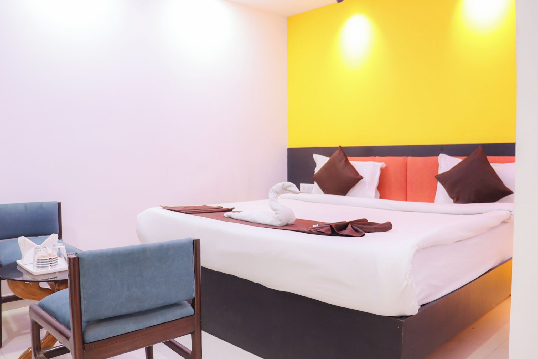 A hotel room with a bed, a chair, and a table with a tray of items.
