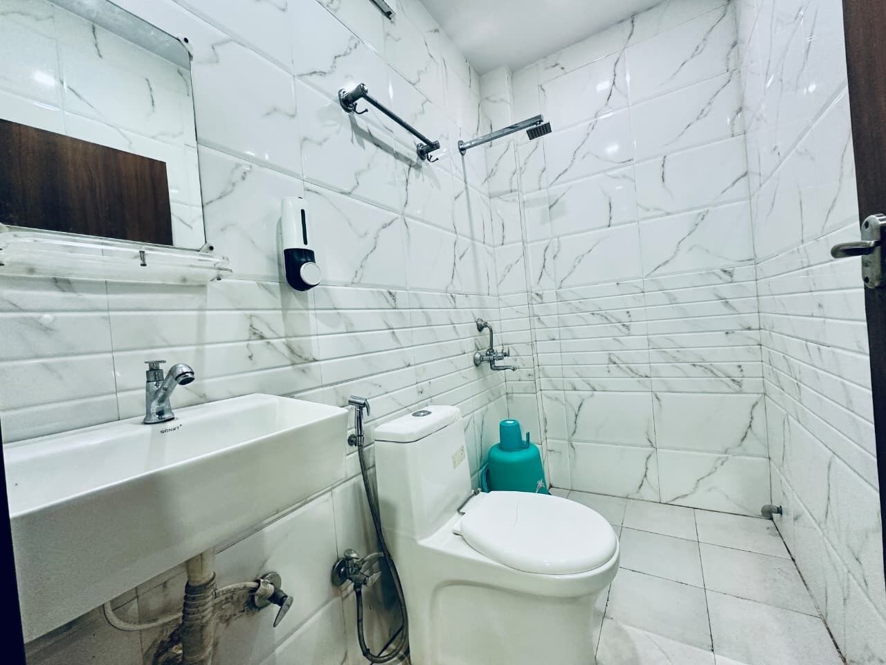 Un baño con azulejos de mármol blanco, un lavabo, un inodoro y una ducha.