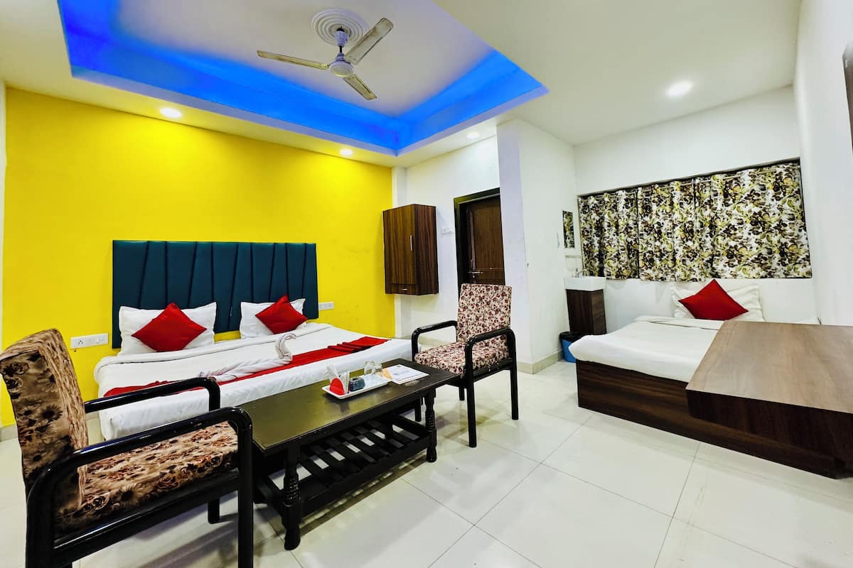 A hotel room with a bed, a desk, two chairs, a ceiling fan, and a window with curtains.