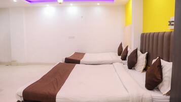 Quarto de hotel com duas camas, uma luminária no teto e uma parede com detalhes em amarelo.