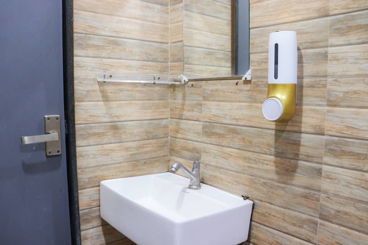 A bathroom with a white sink, a towel rack, and a soap dispenser mounted on the wall.