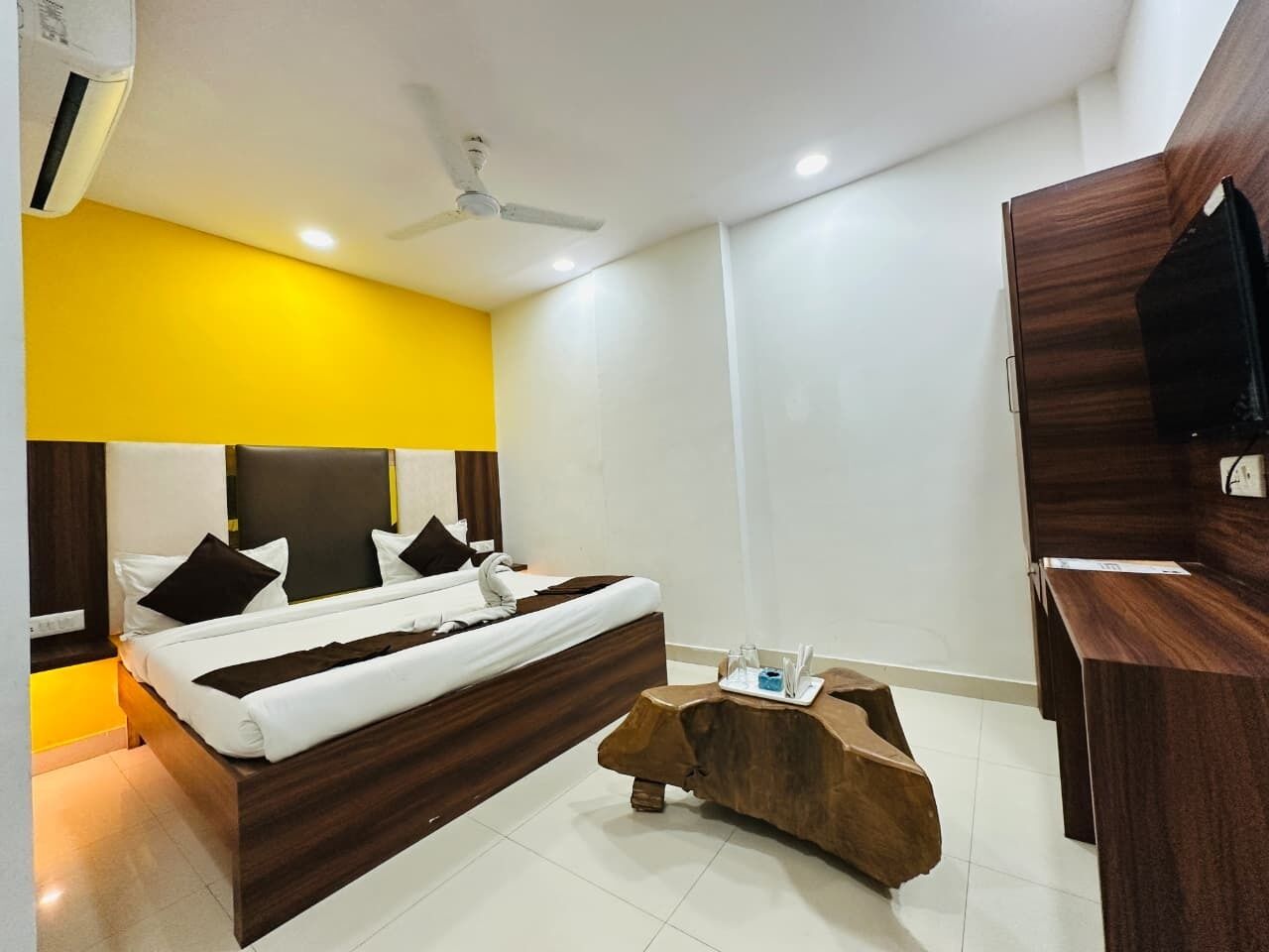 Una habitación de hotel moderna con una cama grande, una mesa de centro de madera y un escritorio con televisor de pantalla plana.