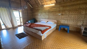 Una habitación de madera con una cama, una mesita pequeña y un banco.