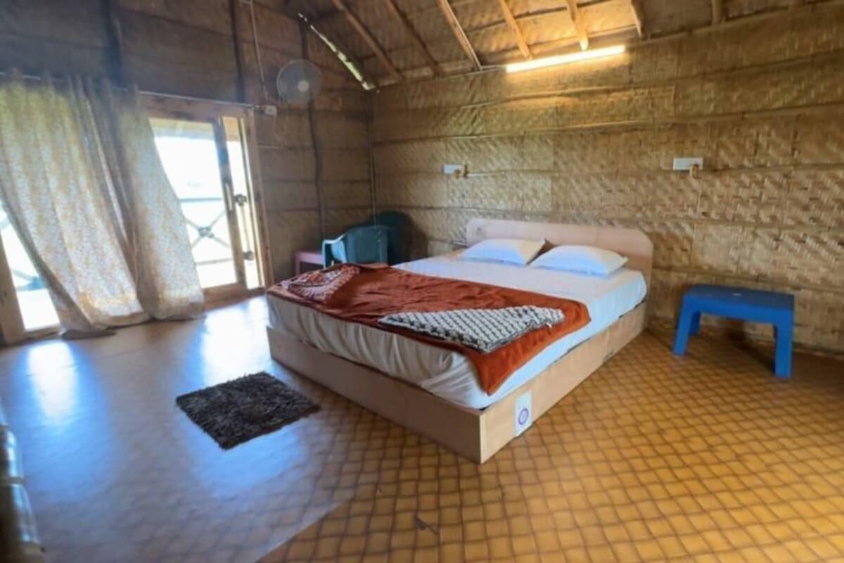 Ein Zimmer aus Holz mit einem Bett, einem kleinen Tisch und einer Bank.