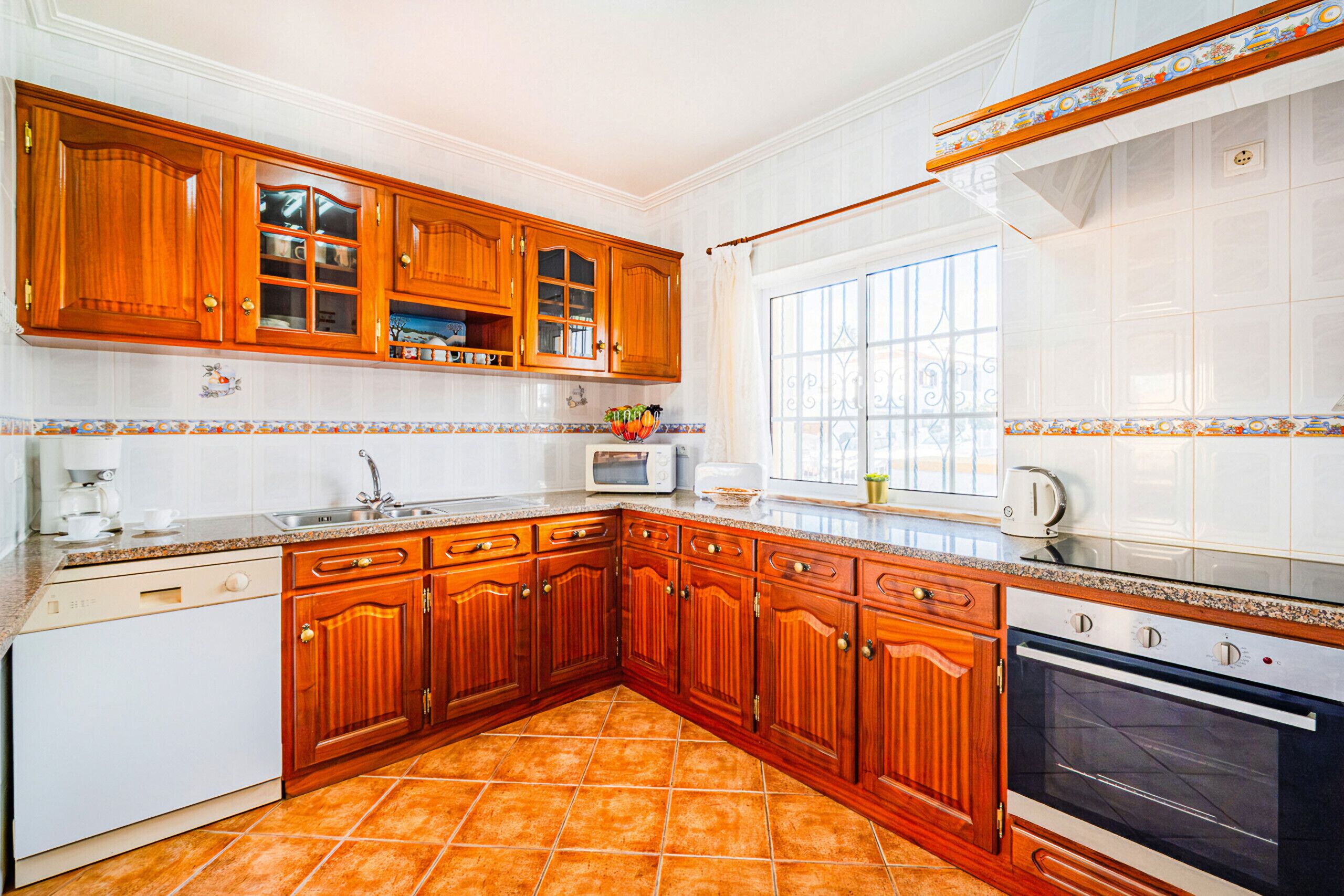 Una cocina con armarios de madera, microondas, tostadora y horno.