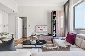 A modern living room with a sofa, coffee table, and a bookshelf. - Stayshort - Beautiful 1 Bed Apartment in Business Bay That Sleeps 4 (Dubai)