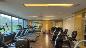 Un gimnasio con varias cintas de correr, elípticas y un muro de espejos.